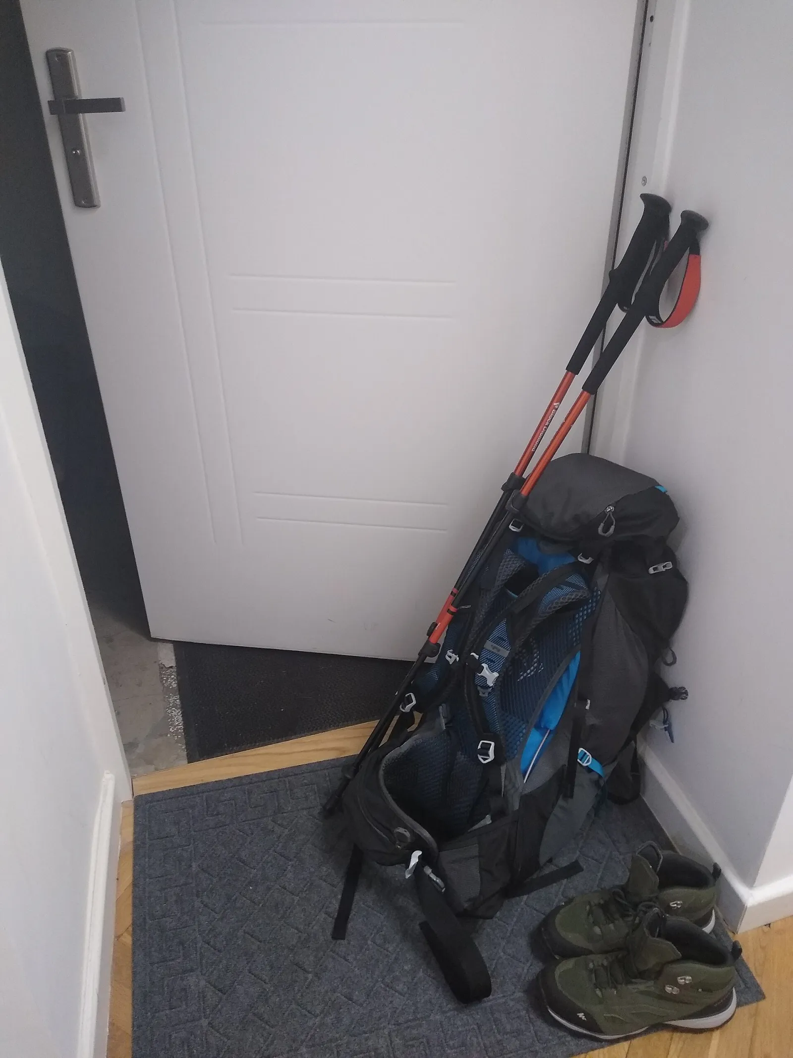 A hiking backpack, trekking poles and trail shoes prepared for a walk