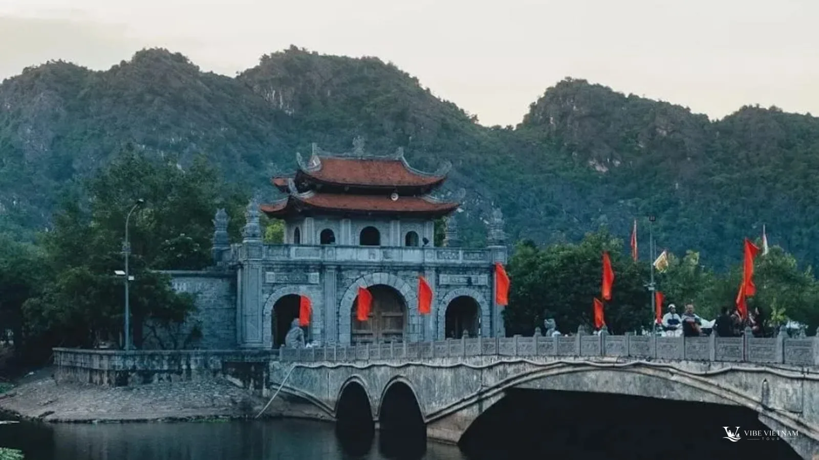 The stone gate and bridge of the Hoa Lu ancient capital, framed by limestone mountains