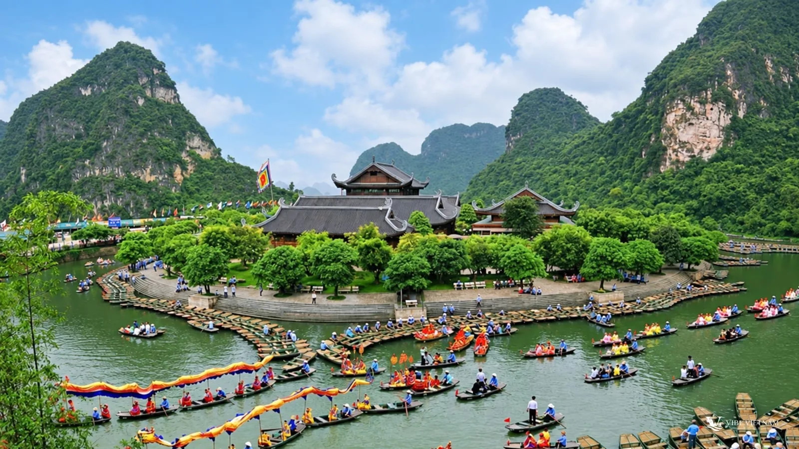 Visitors boarding small boats at the Trang An boat pier below forested limestone cliffs