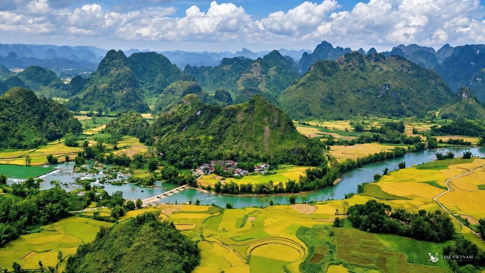 A wide valley of rice fields and a winding river surrounded by limestone mountains