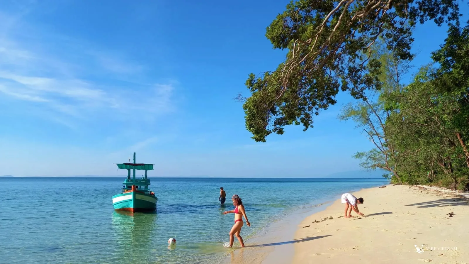 Swimmers and a boat in the shallow water of Sao Beach, Phu Quoc